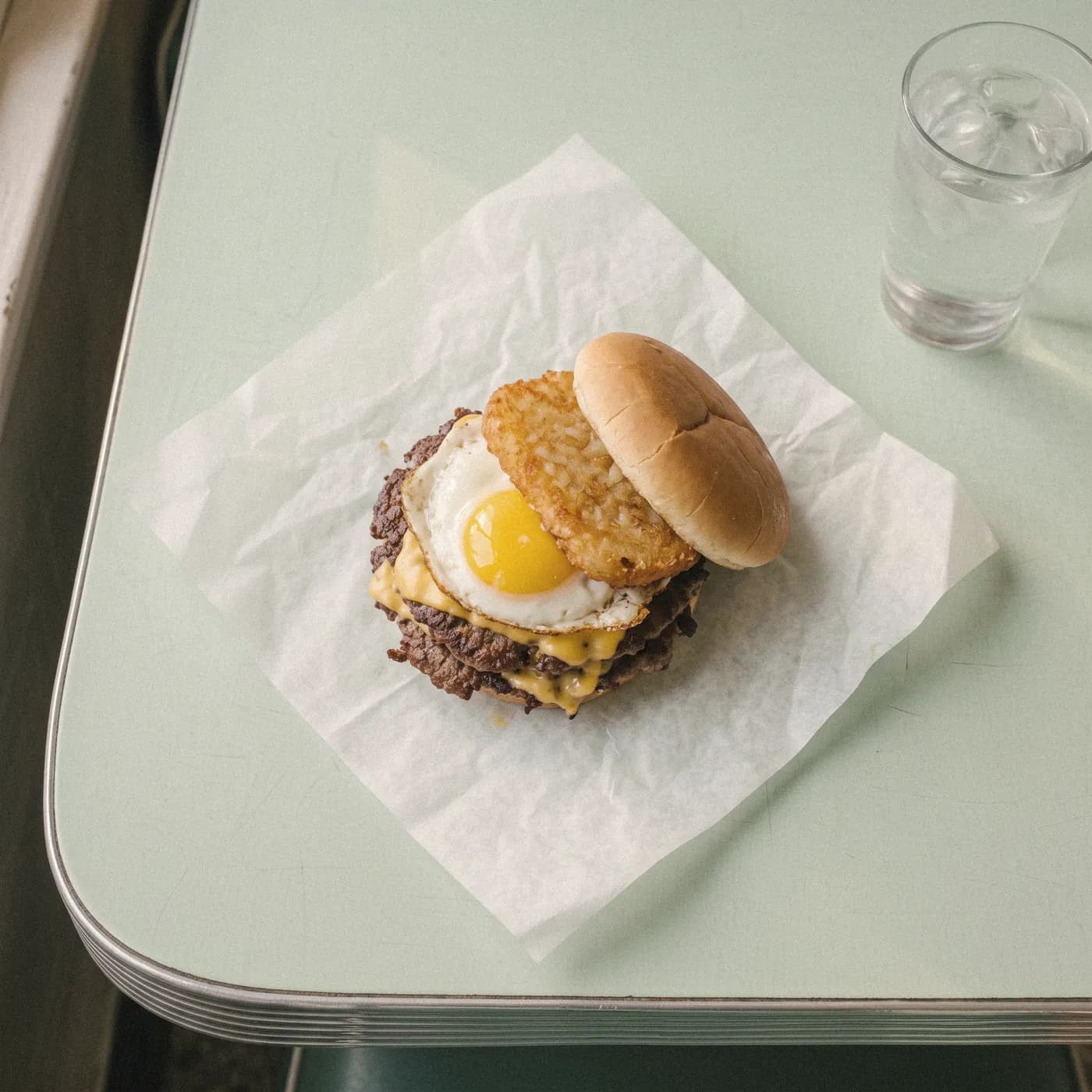 A double cheeseburger topped with a fried egg and a hash brown, seen from above